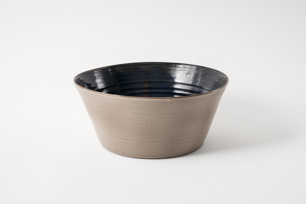 A medium-sized, cobalt glazed ceramic bowl with a simple, elegant design, displayed against a plain background.