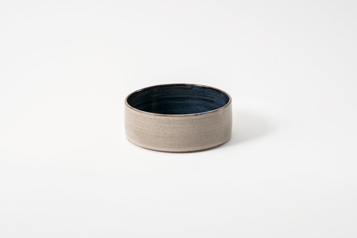 A wheelthrown ceramic bowl with a cobalt glaze, displayed on a plain background.