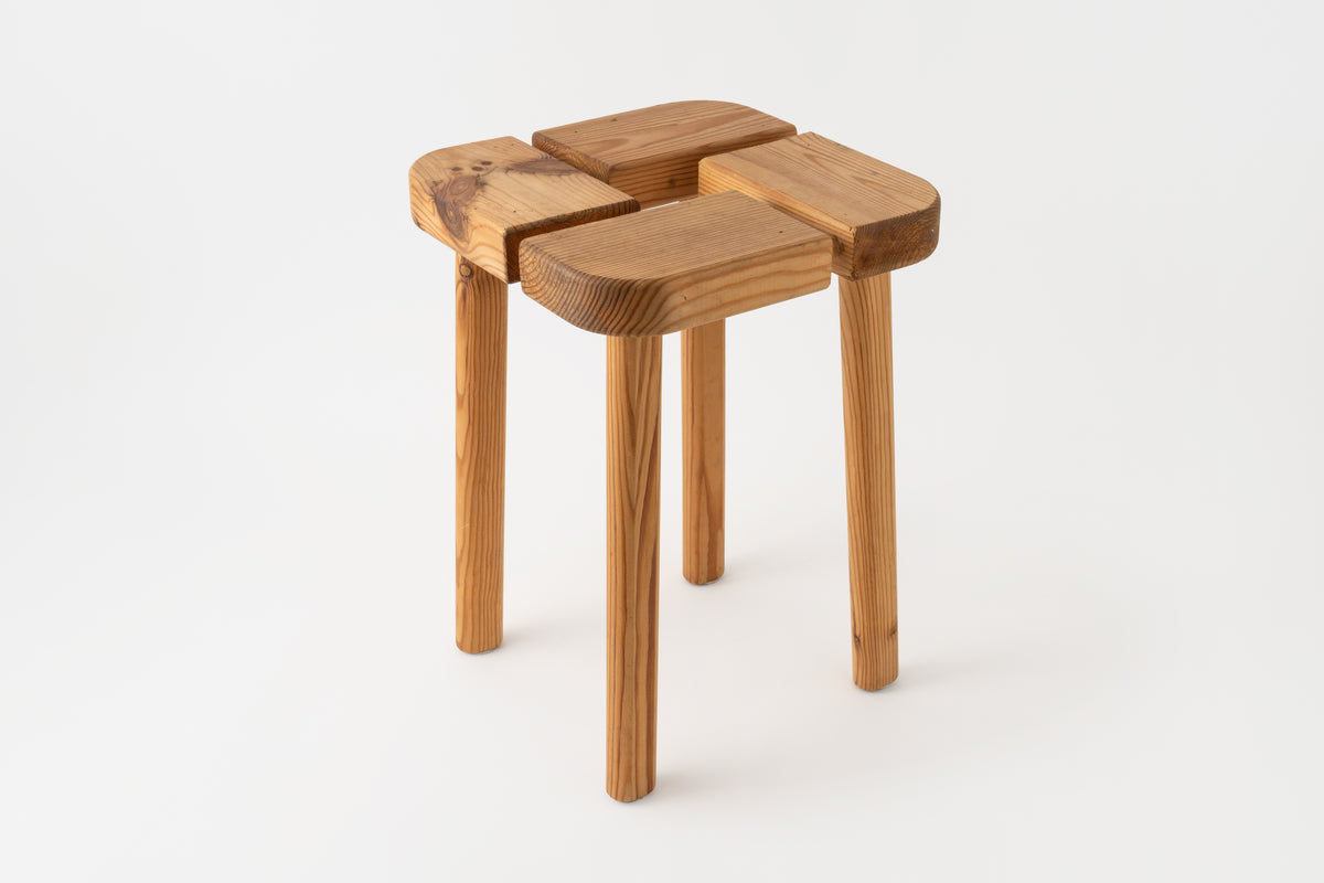A Finnish pine stool with four slightly tilted legs and a doweled top.