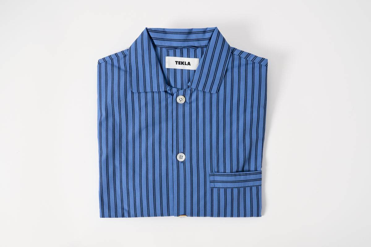 A striped pyjamas shirt in blue and white, laid flat on a white background.