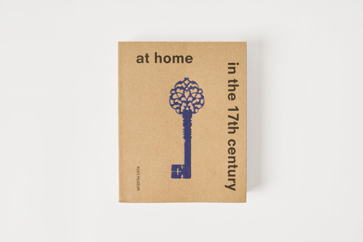 Book titled 'at home in the 17th century' with a decorative key on a beige background