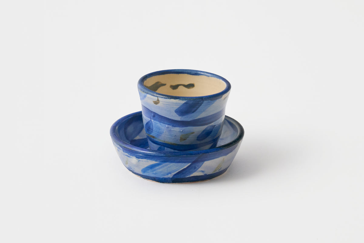 Ceramic teacup and saucer with blue abstract design on a white background