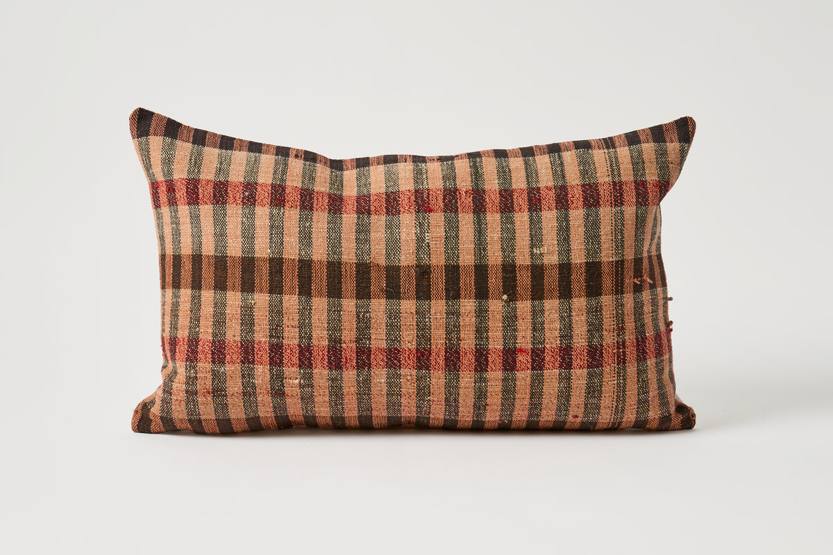 A rectangular lumbar throw pillow with a rustic plaid pattern in brown, beige, and red, shown against a plain light gray background.