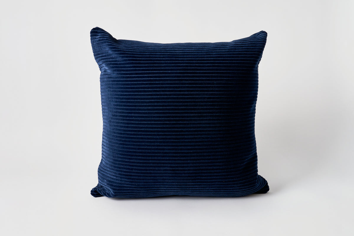 Navy blue ribbed pillow on a white background