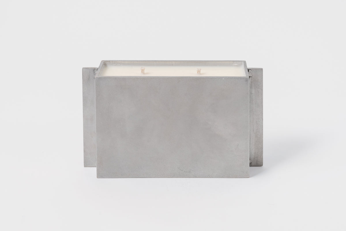 A rectangular metal container holding a triple-wick soy candle, with a grayish-metallic finish.
