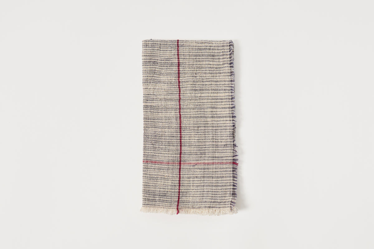 Textured fabric napkin with a red stripe on a white background