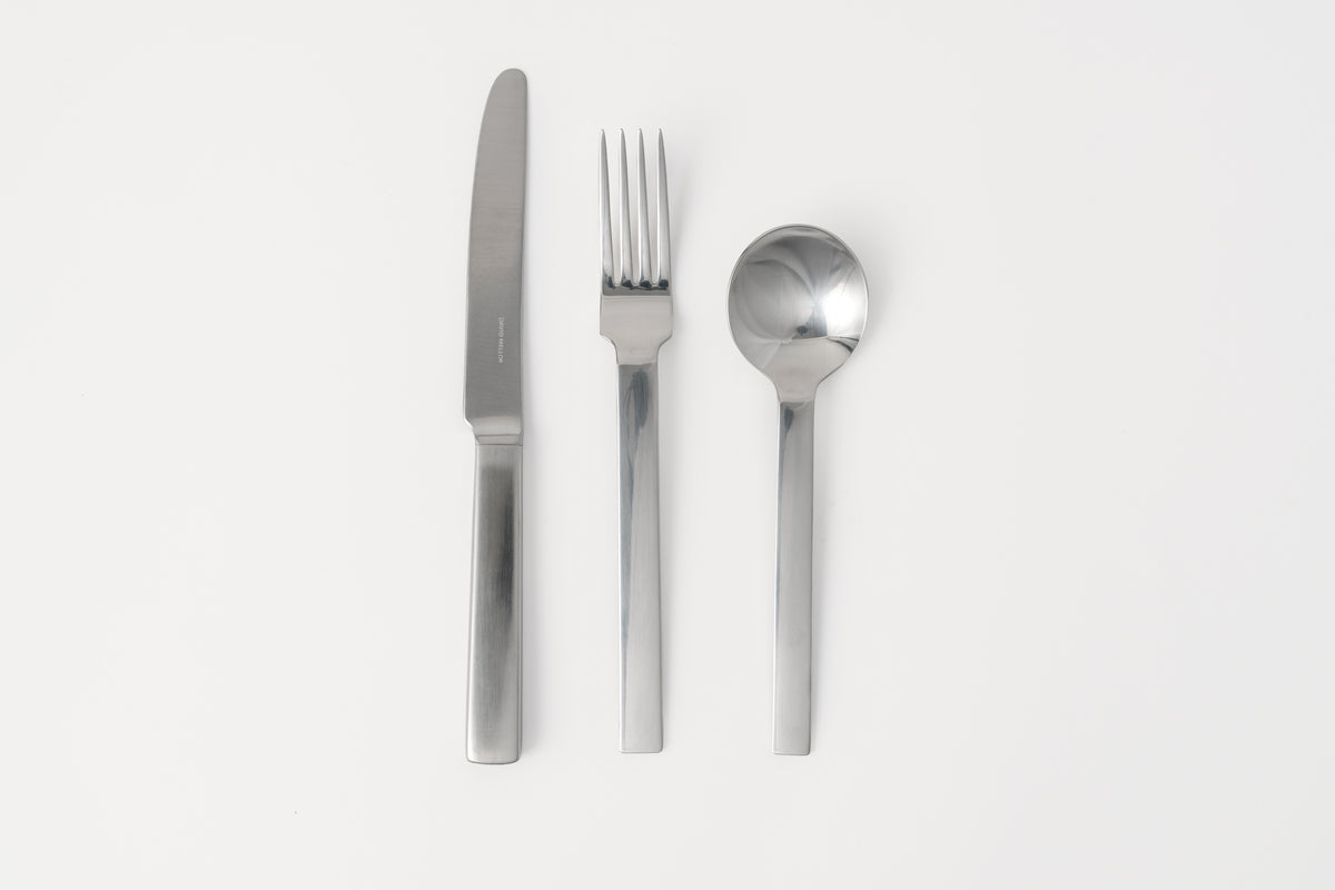 A set of silver flatware including a table knife, table fork, and dessert spoon, displayed on a white background.