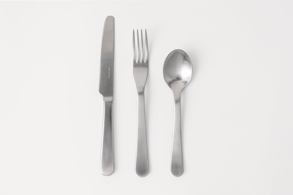 A set of stainless steel cutlery including a table knife, table fork, and dessert spoon, displayed against a white background.
