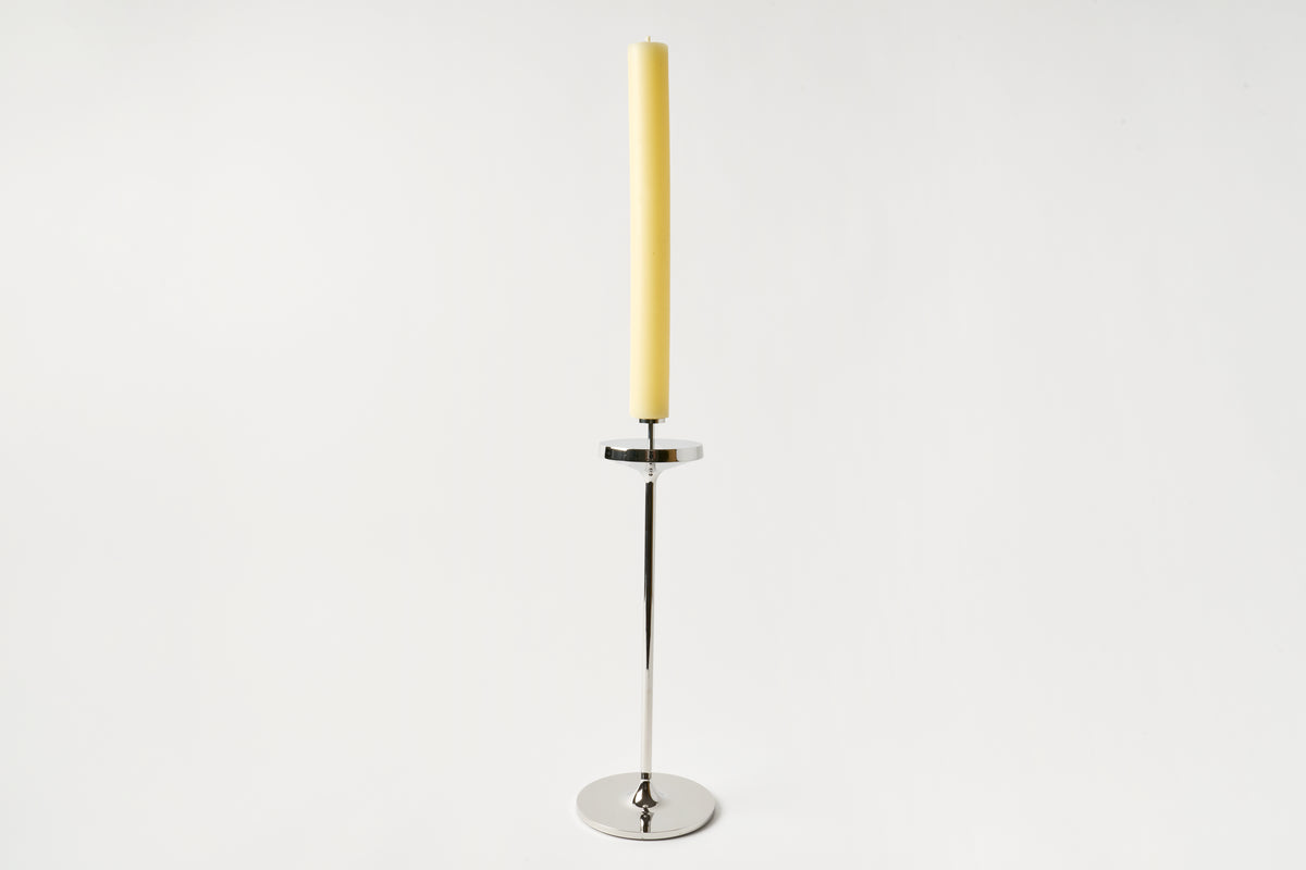 Yellow candle in a metal holder on a white background