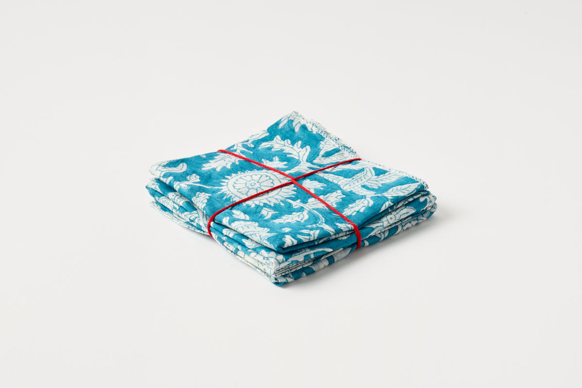 Folded blue and white patterned napkins tied with red string on a light gray background