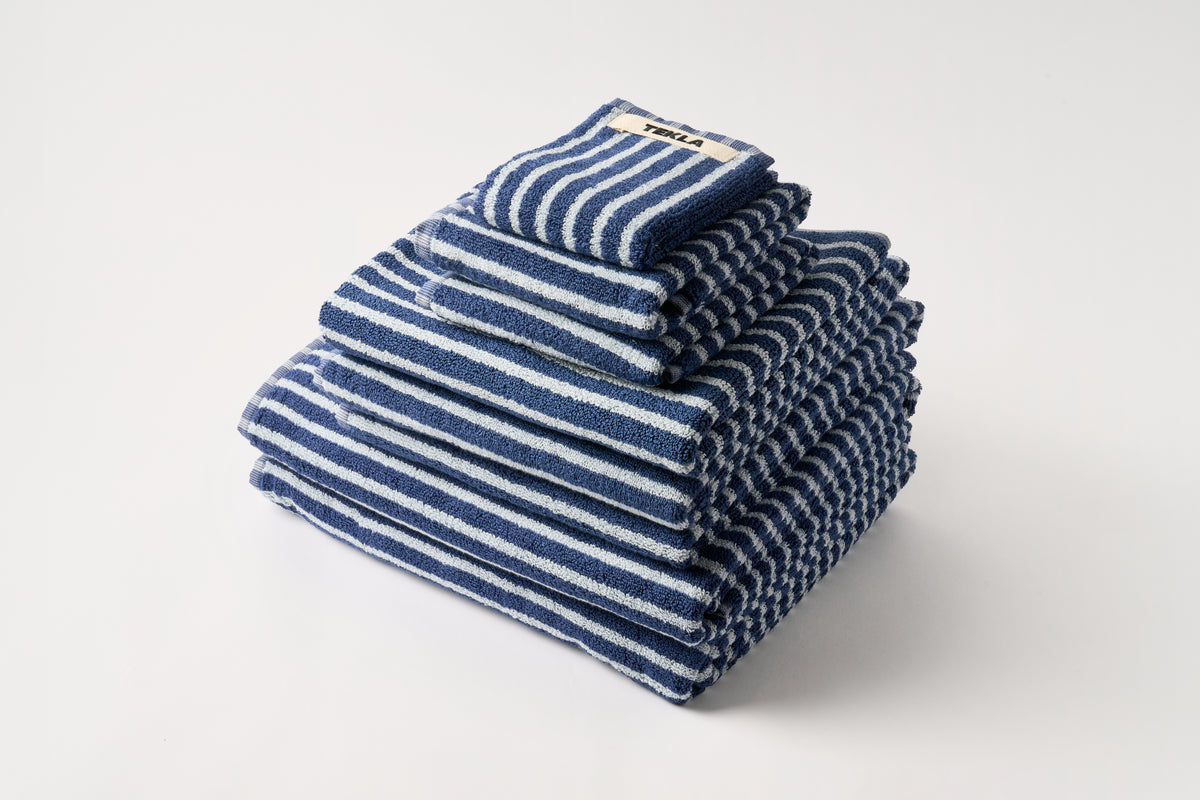 Stack of blue and white striped towels on a light gray background