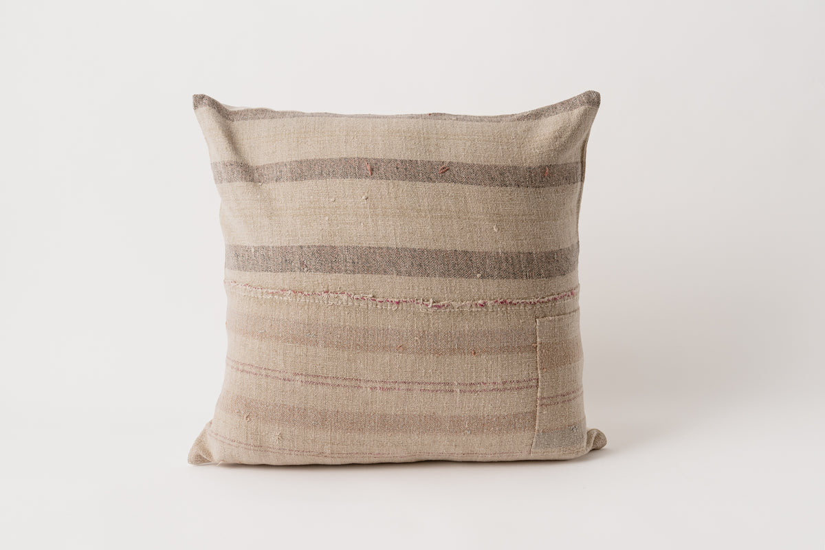 A square-shaped vintage grain sack pillow with beige and brown stripes, handcrafted from a traditional cereal sack.
