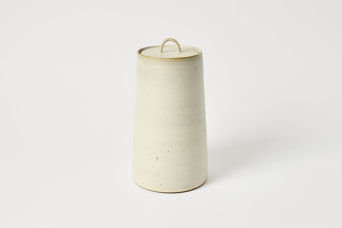 Cylindrical ceramic jar with a lid on a white background