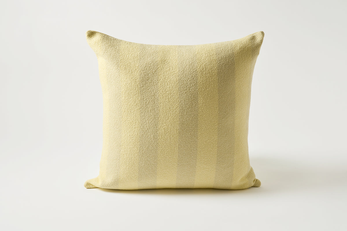A square throw pillow in a pale yellow fabric with subtle vertical stripes, photographed against a clean white studio background.