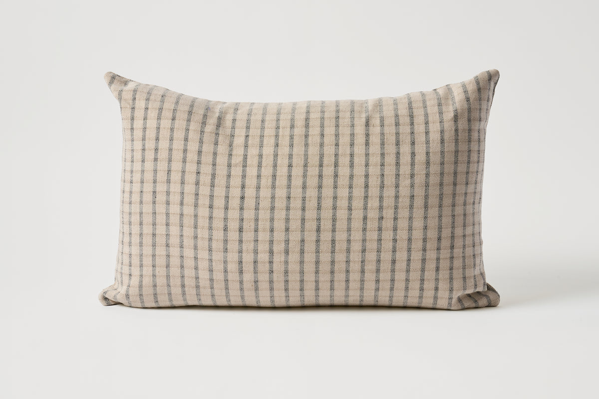 A rectangular throw pillow with a beige and gray checkered pattern, photographed against a neutral light gray background.