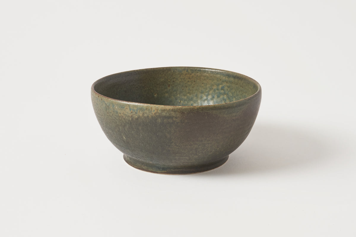 A handmade ceramic bowl with a textured, speckled glaze in earthy olive green and brown tones, photographed on a clean white background.