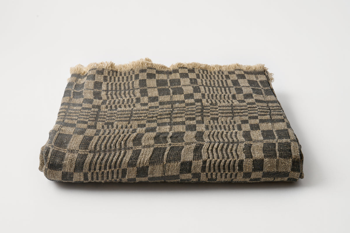 Folded woven blanket with geometric pattern on a white background