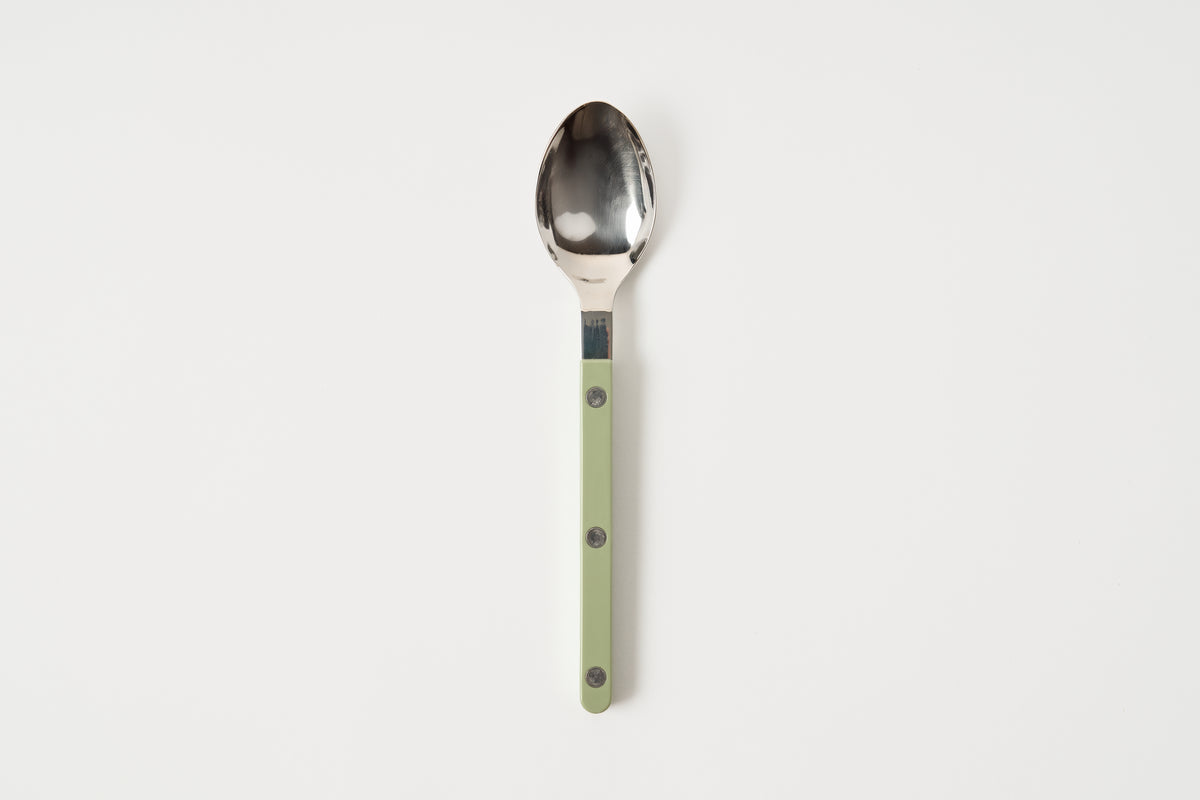 Spoon with a green handle on a white background