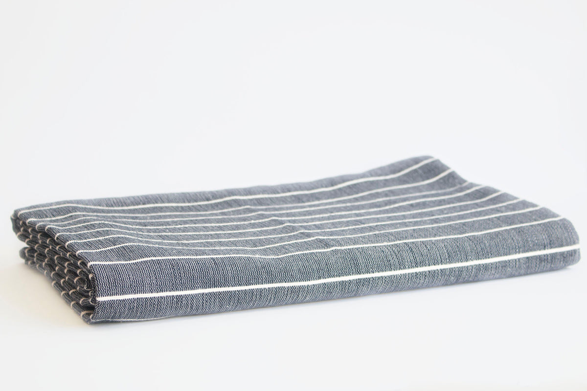 Navy cotton tablecloth with natural stripes, folded and placed on a white background.