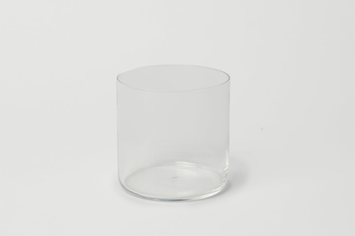A clear, round, short glass tumbler on a white background.